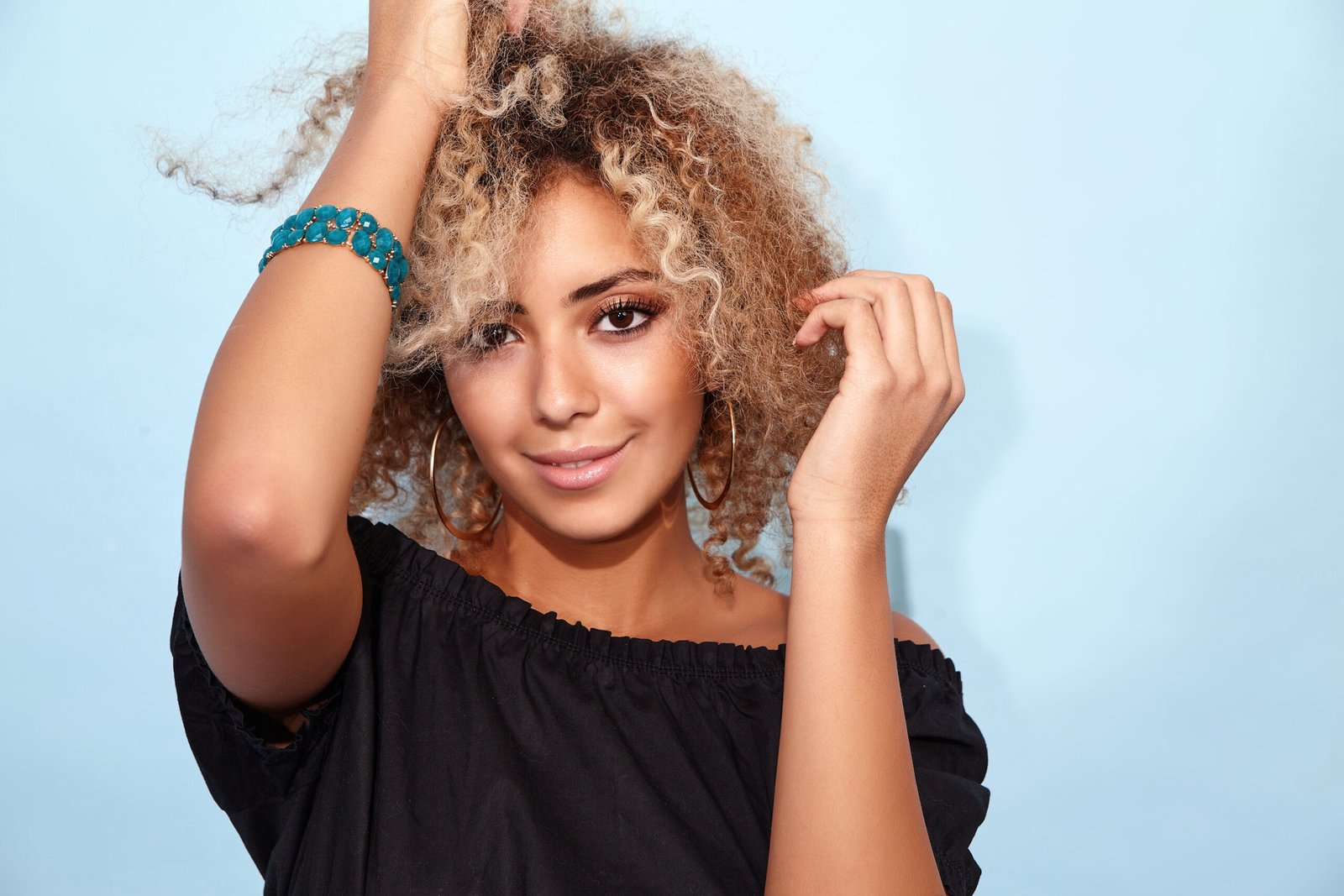 Portrait of blissful sexy hot black woman with blond african hairstyle. Smiling model girl in trendy summer black clothes posing on blue background